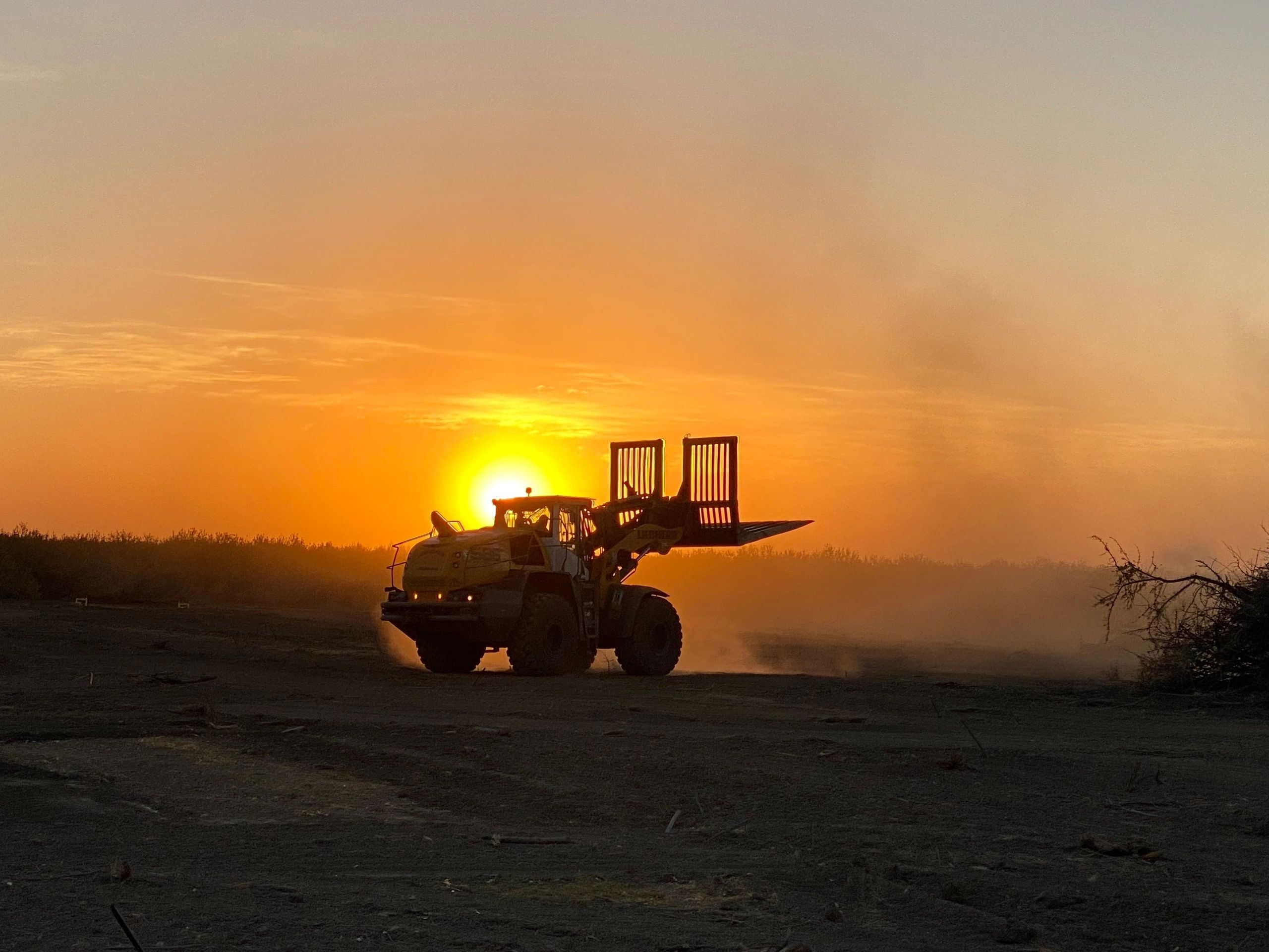 Farm equipment silhouette against golden sunset